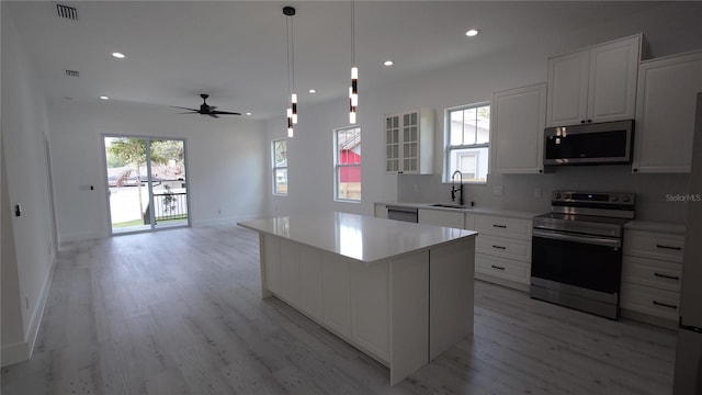 7011 N 15th St, Tampa, FL 33610 - kitchen featuring appliances with stainless steel finishes, a sink, light wood finished floors, white cabinetry, and a ceiling fan