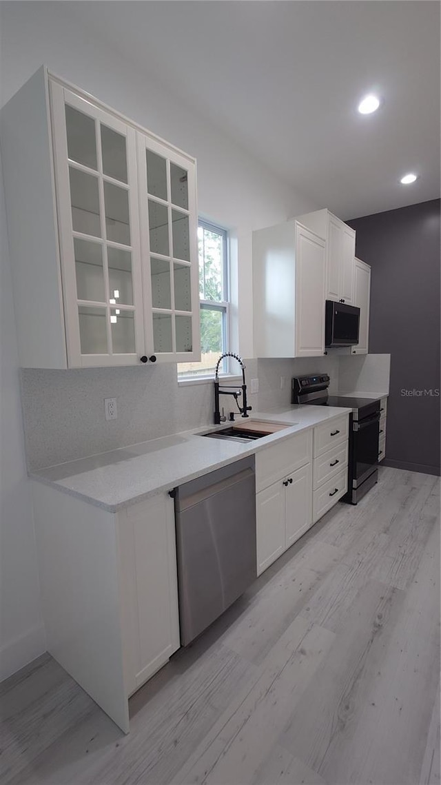 7011 N 15th St, Tampa, FL 33610 - kitchen with range with electric stovetop, black microwave, a sink, dishwasher, and light wood-type flooring