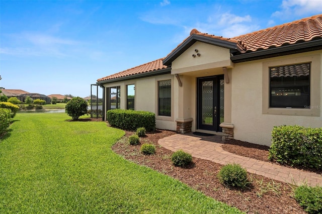 11354 Callisia Dr, Odessa, FL 33556 - view of exterior entry featuring a water view, a lawn, stucco siding, and a tile roof