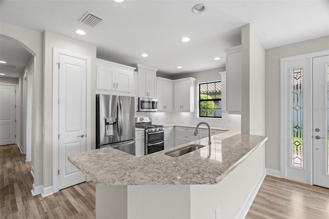 11354 Callisia Dr, Odessa, FL 33556 - kitchen featuring appliances with stainless steel finishes, a sink, light wood-type flooring, arched walkways, and recessed lighting