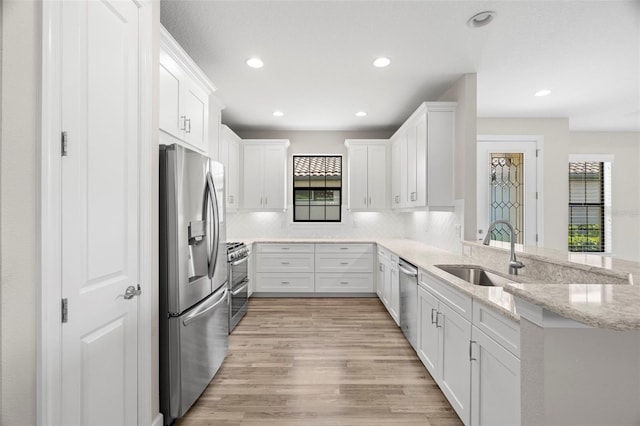 11354 Callisia Dr, Odessa, FL 33556 - kitchen with appliances with stainless steel finishes, a sink, a peninsula, white cabinets, and tasteful backsplash