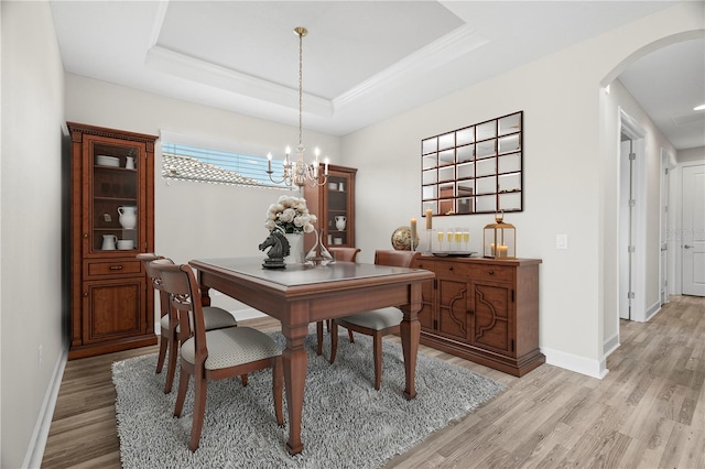 11354 Callisia Dr, Odessa, FL 33556 - dining area with arched walkways, light wood-style floors, baseboards, a tray ceiling, and a chandelier