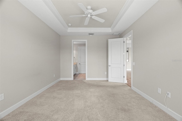 11354 Callisia Dr, Odessa, FL 33556 - unfurnished bedroom featuring a raised ceiling, light carpet, baseboards, ensuite bath, and a ceiling fan