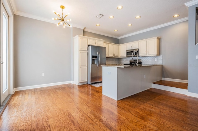 102 S Moody Ave Unit 1, Tampa, FL 33609 - kitchen featuring appliances with stainless steel finishes, decorative backsplash, a peninsula, a chandelier, and light wood finished floors