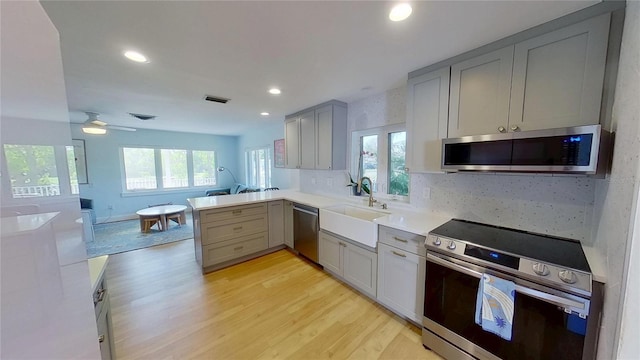 1200 47th St N, Saint Petersburg, FL 33713 - kitchen featuring appliances with stainless steel finishes, gray cabinets, a sink, light wood-type flooring, and healthy amount of natural light