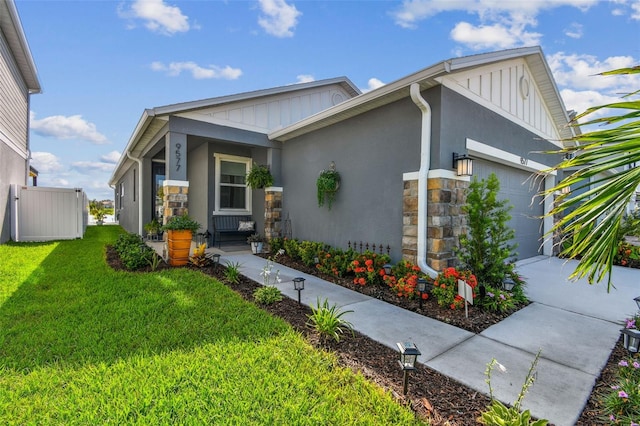 9577 Sandy Bluffs Cir, Parrish, FL 34219 - view of side of home with stone siding, board and batten siding, a garage, and driveway