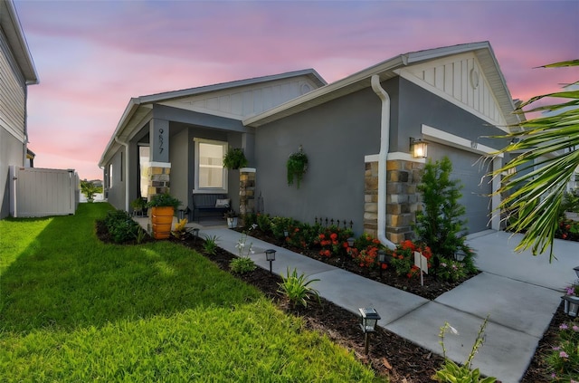 9577 Sandy Bluffs Cir, Parrish, FL 34219 - view of front of home with stone siding, board and batten siding, a garage, and a yard