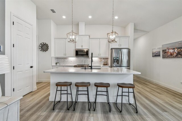9577 Sandy Bluffs Cir, Parrish, FL 34219 - kitchen with stainless steel appliances, a sink, an island with sink, a breakfast bar area, and tasteful backsplash
