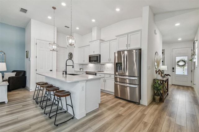 9577 Sandy Bluffs Cir, Parrish, FL 34219 - kitchen with stainless steel appliances, a sink, a kitchen breakfast bar, light wood-type flooring, and light countertops