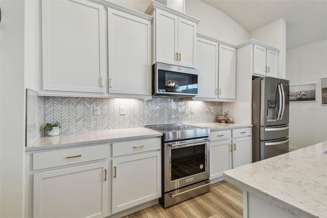 9577 Sandy Bluffs Cir, Parrish, FL 34219 - kitchen featuring appliances with stainless steel finishes, white cabinets, light wood-type flooring, and tasteful backsplash