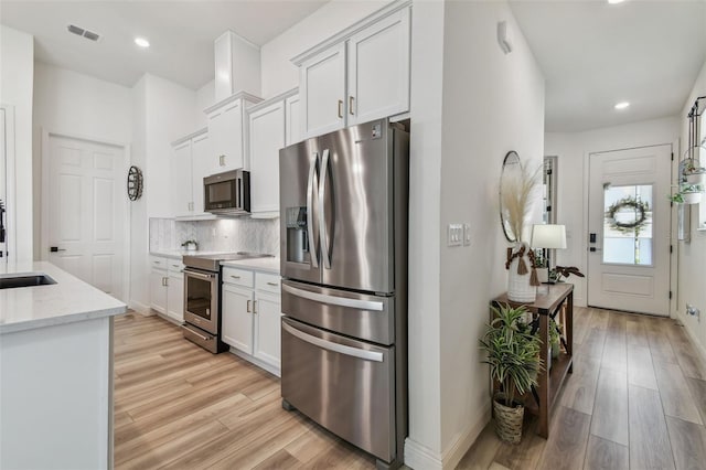 9577 Sandy Bluffs Cir, Parrish, FL 34219 - kitchen featuring appliances with stainless steel finishes, light wood-style floors, white cabinets, decorative backsplash, and recessed lighting