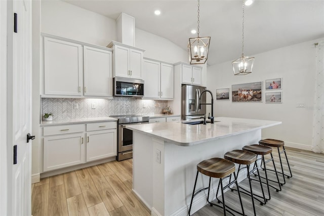 9577 Sandy Bluffs Cir, Parrish, FL 34219 - kitchen with appliances with stainless steel finishes, a sink, light wood-style floors, white cabinetry, and decorative backsplash