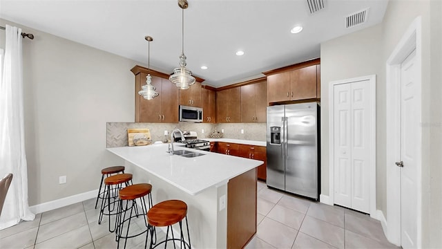 6118 Voyagers Pl, Apollo Beach, FL 33572 - kitchen featuring appliances with stainless steel finishes, light tile patterned flooring, a breakfast bar area, light countertops, and a peninsula