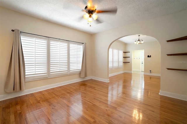6419 S Englewood Ave, Tampa, FL 33611 - empty room featuring arched walkways, a ceiling fan, a chandelier, light wood-style floors, and a textured ceiling