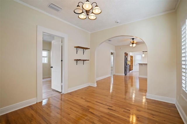 6419 S Englewood Ave, Tampa, FL 33611 - spare room featuring a chandelier, light wood-type flooring, arched walkways, a textured ceiling, and crown molding