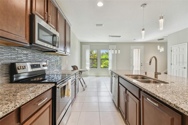 13311 Dorado Shores Ave, Riverview, FL 33579 - kitchen featuring appliances with stainless steel finishes, a sink, decorative backsplash, hanging light fixtures, and light tile patterned floors