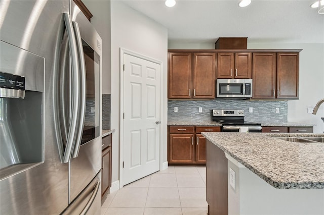 13311 Dorado Shores Ave, Riverview, FL 33579 - kitchen featuring appliances with stainless steel finishes, a sink, backsplash, light tile patterned flooring, and light stone countertops