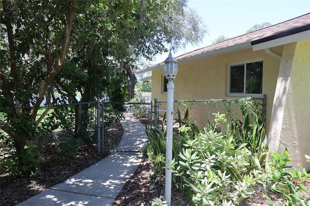 12929 Sugar Creek Blvd, Hudson, FL 34669 - view of home's exterior with stucco siding, a shingled roof, and a gate
