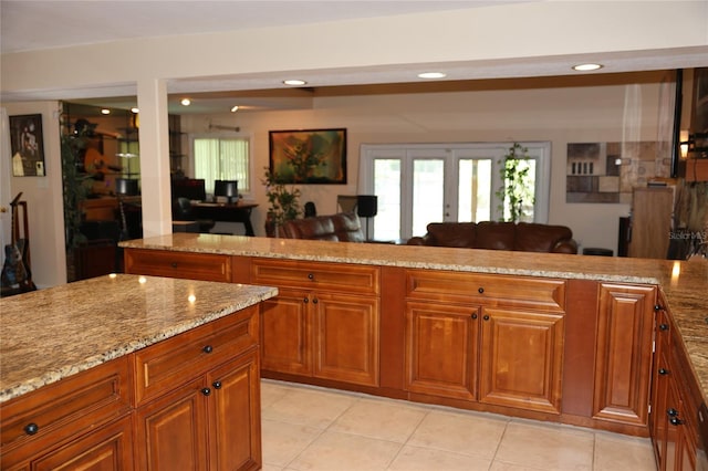 12929 Sugar Creek Blvd, Hudson, FL 34669 - kitchen with light stone countertops, brown cabinets, light tile patterned floors, recessed lighting, and open floor plan