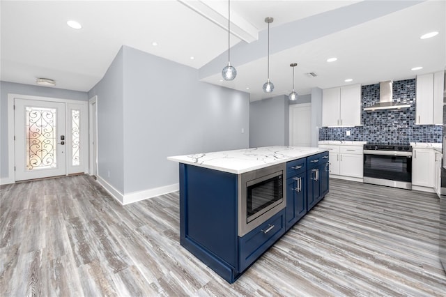 9909 San Mateo Way, Port Richey, FL 34668 - kitchen with stainless steel appliances, wall chimney range hood, blue cabinetry, white cabinets, and recessed lighting