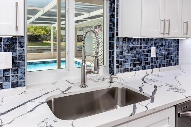 9909 San Mateo Way, Port Richey, FL 34668 - kitchen featuring a sink, white cabinetry, tasteful backsplash, and light stone countertops