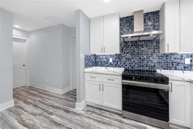 9909 San Mateo Way, Port Richey, FL 34668 - kitchen with electric range oven, wall chimney range hood, tasteful backsplash, light stone countertops, and white cabinetry