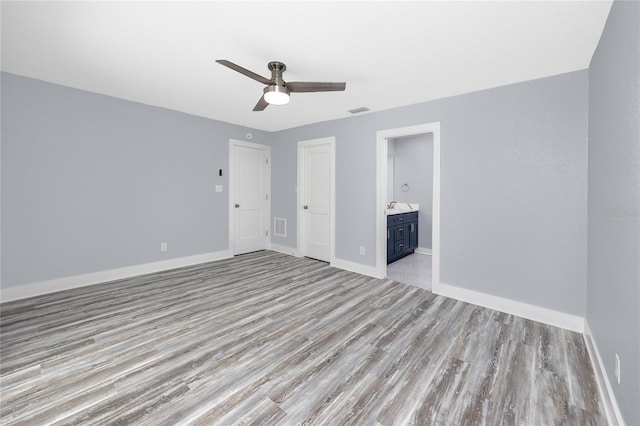 9909 San Mateo Way, Port Richey, FL 34668 - unfurnished bedroom with light wood-style flooring, baseboards, ensuite bathroom, and ceiling fan