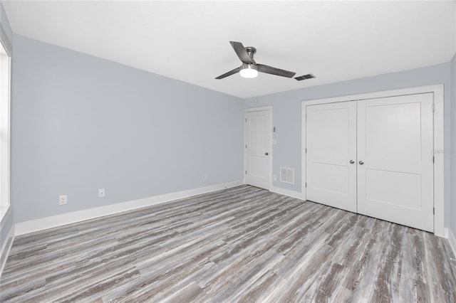 9909 San Mateo Way, Port Richey, FL 34668 - unfurnished bedroom with wood finished floors, baseboards, a closet, and ceiling fan