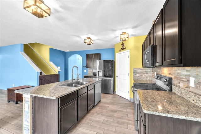 14135 Arbor Pines Dr, Riverview, FL 33579 - kitchen with stainless steel appliances, a sink, light wood-type flooring, decorative backsplash, and a textured ceiling