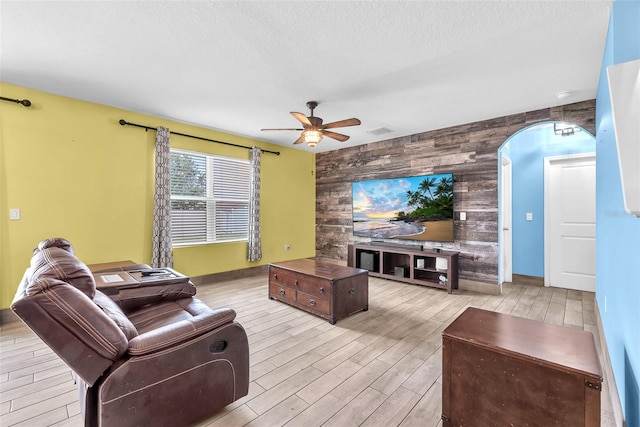 14135 Arbor Pines Dr, Riverview, FL 33579 - living room featuring an accent wall, wooden walls, a ceiling fan, wood finished floors, and a textured ceiling