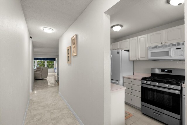 3114 59th St S Unit 203, Gulfport, FL 33707 - kitchen with white appliances, white cabinetry, light marble finish flooring, baseboards, and light countertops