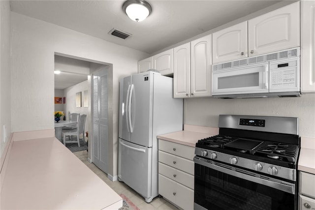 3114 59th St S Unit 203, Gulfport, FL 33707 - kitchen featuring white appliances, white cabinets, light countertops, and light tile patterned floors