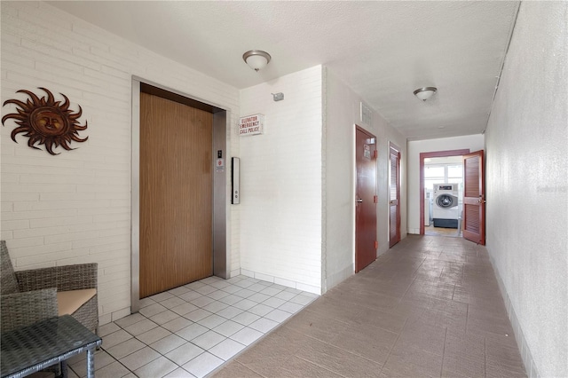 3114 59th St S Unit 203, Gulfport, FL 33707 - corridor featuring washer / dryer, elevator, light tile patterned floors, and a textured ceiling