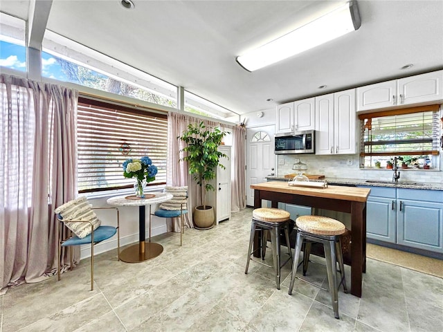 6700 14th St N, Saint Petersburg, FL 33702 - kitchen featuring stainless steel microwave, wooden counters, a sink, backsplash, and white cabinetry