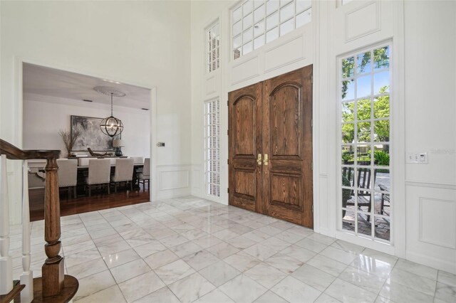 16502 Millan De Avila, Tampa, FL 33613 - foyer featuring a decorative wall, a chandelier, crown molding, a wainscoted wall, and a towering ceiling