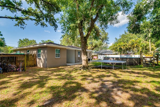 1403 W Pradera Ave, Tampa, FL 33612 - rear view of house with a trampoline and stucco siding