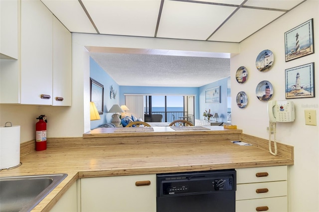 14950 Gulf Blvd Unit 905, Madeira Beach, FL 33708 - kitchen with black dishwasher, wood counters, a peninsula, and white cabinetry