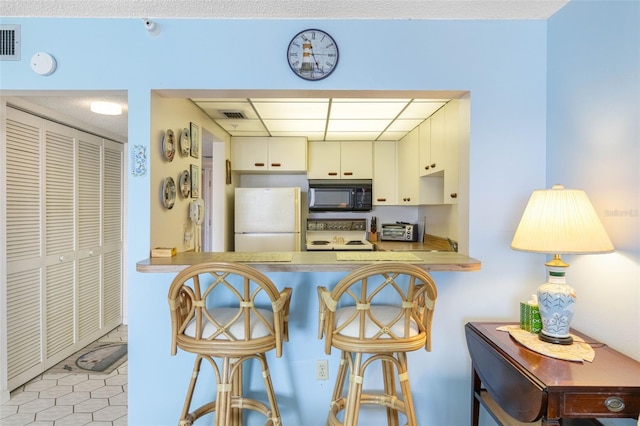 14950 Gulf Blvd Unit 905, Madeira Beach, FL 33708 - kitchen featuring freestanding refrigerator, black microwave, range, a paneled ceiling, and a peninsula