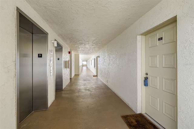 14950 Gulf Blvd Unit 905, Madeira Beach, FL 33708 - hallway with a textured wall, a textured ceiling, elevator, and concrete flooring