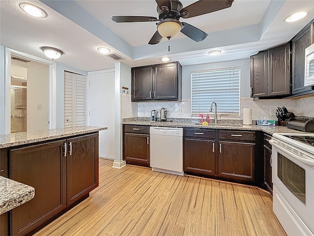 4725 Cove Cir Unit 908, Saint Petersburg, FL 33708 - kitchen featuring white appliances, light wood-style flooring, a raised ceiling, dark brown cabinetry, and recessed lighting