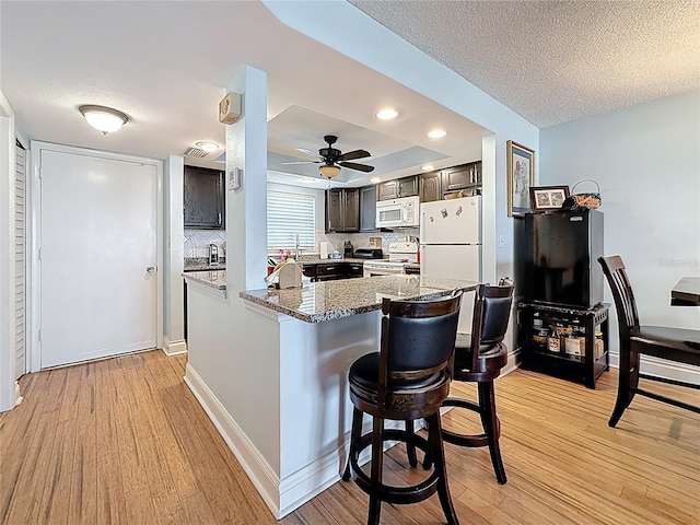 4725 Cove Cir Unit 908, Saint Petersburg, FL 33708 - kitchen featuring white appliances, light wood-style floors, a peninsula, dark brown cabinets, and a textured ceiling