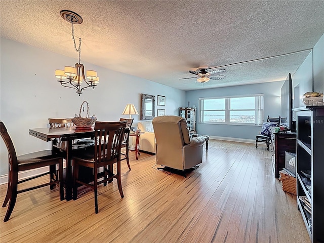 4725 Cove Cir Unit 908, Saint Petersburg, FL 33708 - dining space with a textured ceiling, light wood-style floors, a chandelier, ceiling fan, and baseboards