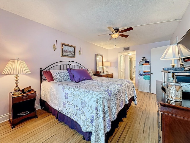 4725 Cove Cir Unit 908, Saint Petersburg, FL 33708 - bedroom featuring light wood finished floors, a textured ceiling, ensuite bath, ceiling fan, and baseboards