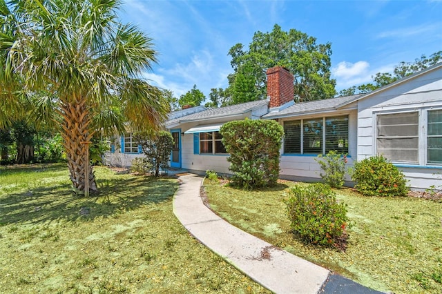 601 75th St N, Saint Petersburg, FL 33710 - view of front facade featuring a chimney and a front lawn