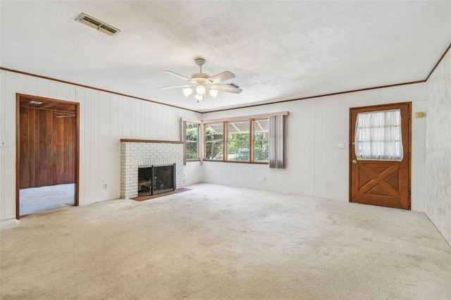 601 75th St N, Saint Petersburg, FL 33710 - unfurnished living room featuring crown molding, carpet flooring, a ceiling fan, a brick fireplace, and wood walls