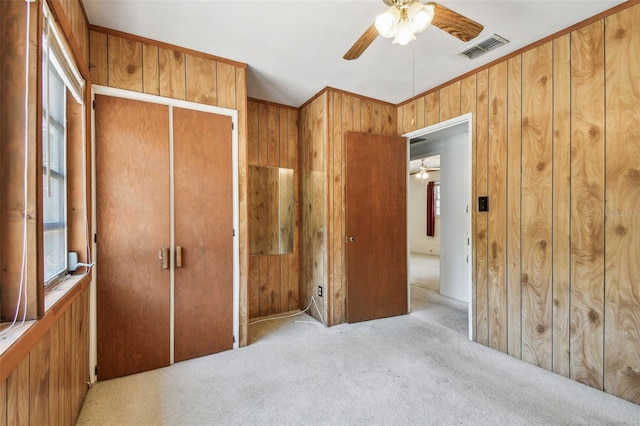 601 75th St N, Saint Petersburg, FL 33710 - unfurnished bedroom with wooden walls, carpet, multiple windows, a ceiling fan, and crown molding
