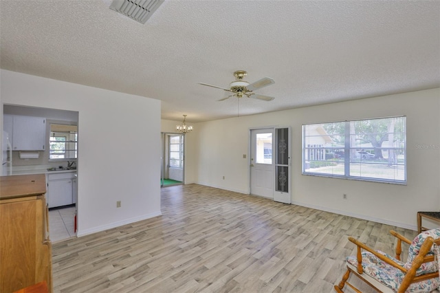1904 Canterbury Ln Unit 18, Sun City Center, FL 33573 - unfurnished living room featuring a chandelier, light wood-style floors, a textured ceiling, plenty of natural light, and a sink
