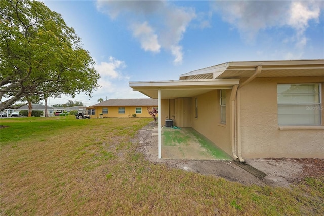 1904 Canterbury Ln Unit 18, Sun City Center, FL 33573 - view of grassy yard with central air condition unit, an attached carport, and a patio