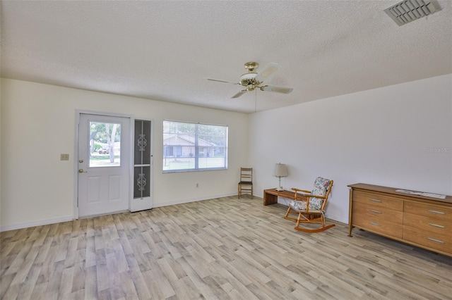 1904 Canterbury Ln Unit 18, Sun City Center, FL 33573 - living area with light wood-type flooring, a textured ceiling, ceiling fan, and baseboards