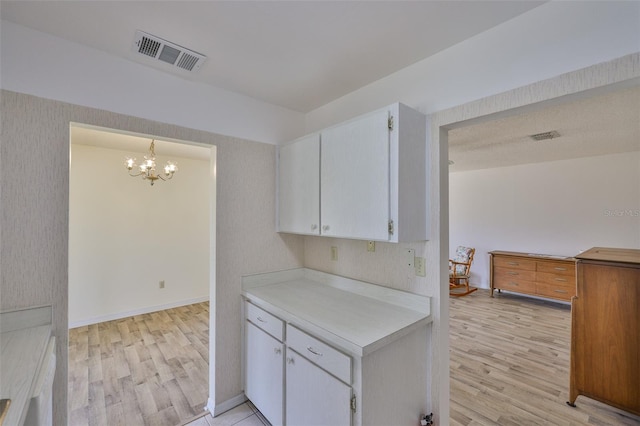1904 Canterbury Ln Unit 18, Sun City Center, FL 33573 - kitchen featuring light wood-type flooring, light countertops, a chandelier, and white cabinetry